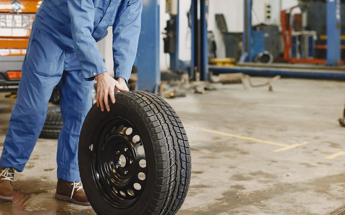 Mechanic handling a tyre in an automotive workshop